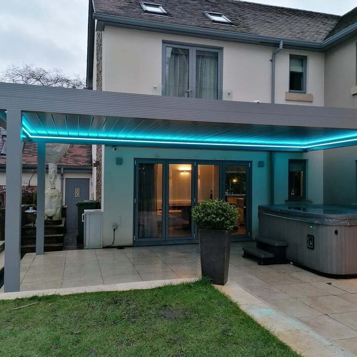 Solid looking Bespoke Aluminium Pergola with LED Lighting against a building - covering a Hot Tub