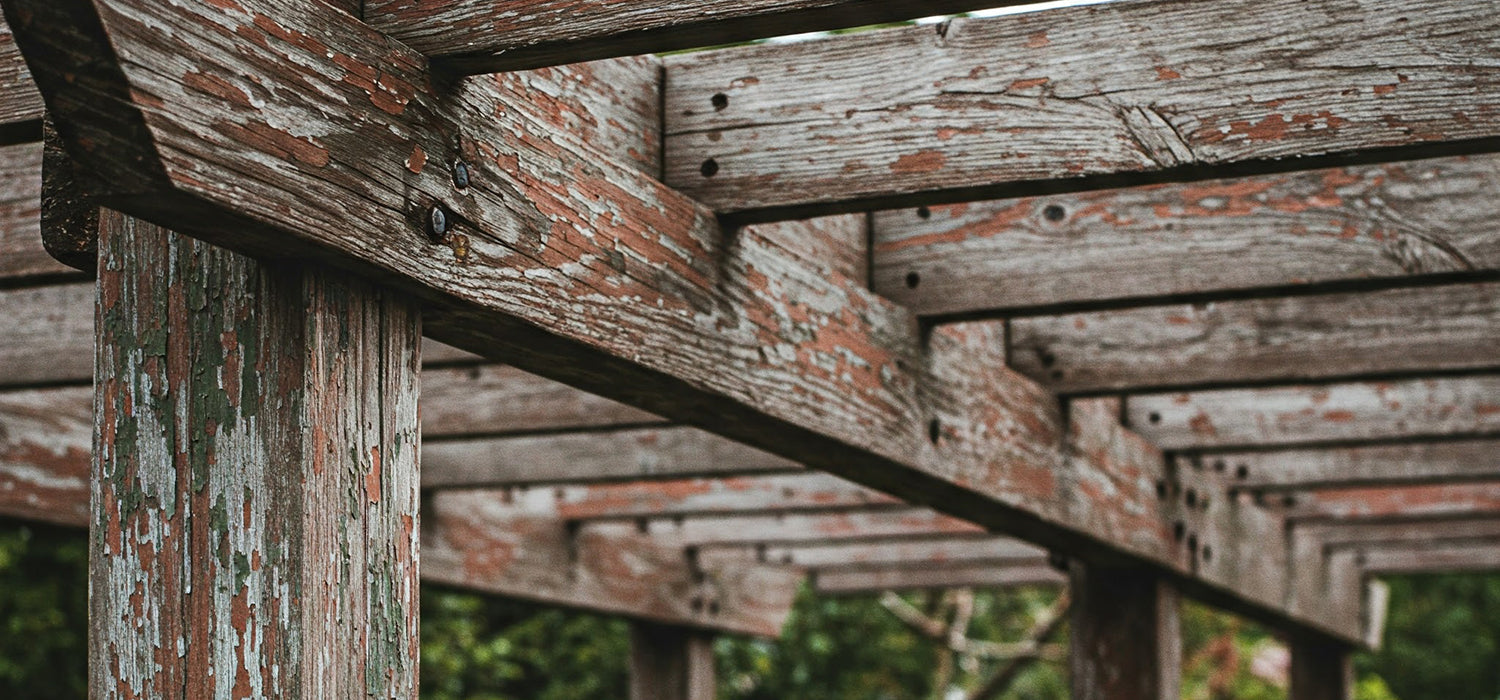 Weathered wooden pergola with peeling paint.