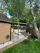 Back garden with a patio area, pergola, and outdoor furniture under a tree.