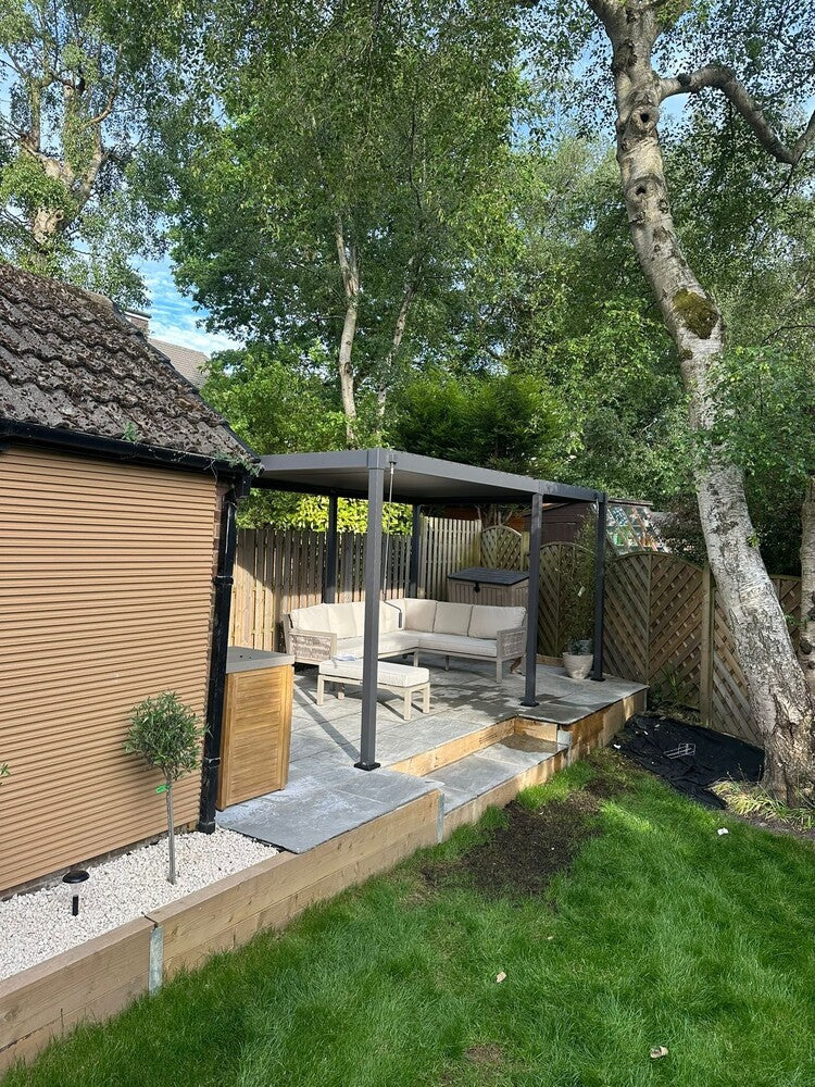 Back garden with a patio area, pergola, and outdoor furniture under a tree.