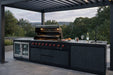 Nova Assado Plus Outdoor Kitchen under pergola on landscaped patio with a view and grill lid open