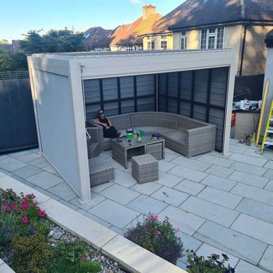 Outdoor patio area with wicker furniture and a person sitting on a bench.